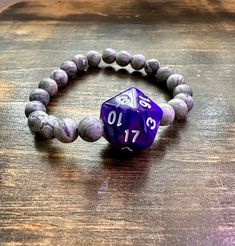 "DnD Inspired Jewelry! Jasper beads and purple D20 Stretch Bracelet  Average bracelet size for women is 7\" and for men 8\" printable ruler - https://printable-ruler.net/ Add 1/4 inch to 1 inch (average is 1/2 inch) to your wrist size, depending on whether you would like a snug, comfort, or loose fit." Purple Beaded Wristband Gift, Purple Beaded Wristband For Gift, Adjustable Purple Wristband With Round Beads, Handmade Purple Beads For Gifts, Dnd Bracelet, Printable Ruler, Dnd Gifts, Critical Role, Inspired Jewelry