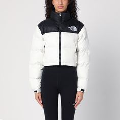 White nylon cropped down jacket from The North Face, featuring a high collar, a zip front fastening, an embroidered logo on the chest and back, two front zipped pockets and a drawstring at the bottom. White Nylon Puffer Jacket With Padded Collar, Cropped White Winter Outerwear, White Cropped Outerwear For Winter, White Puffer Jacket With Zipper For Outdoor, White Puffer Jacket With Padded Collar For Outdoor, White Outdoor Puffer Jacket With Zipper Closure, White Sporty Puffer Jacket With Padded Collar, Casual White Nylon Puffer Jacket, Sporty White Outerwear With Padded Collar