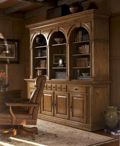 a large wooden cabinet sitting in the middle of a living room next to a chair