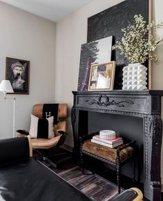 a living room with a black fireplace and pictures on the wall, leather chair and ottoman