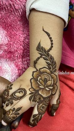 a woman's hand with henna tattoos on it and flowers painted on the palm