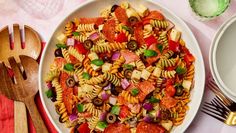 a bowl filled with pasta salad next to two forks