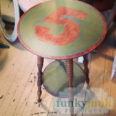 a small table with the number five painted on it's top, sitting in front of a mirror