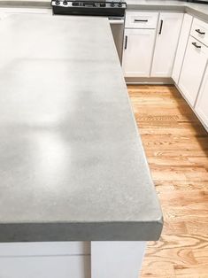 a kitchen counter top with white cabinets and wood flooring in front of an oven