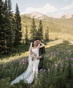 a bride and groom standing in the mountains