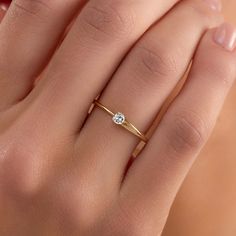 a woman's hand with a diamond ring on top of her finger and the other hand holding it