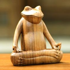 a wooden statue of a frog sitting in a lotus position