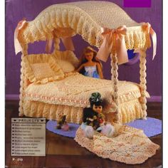 a crocheted bed with a doll sitting on top of it next to a table