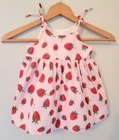 This fun and summery strawberry sundress with matching bloomers for babies and toddlers features a full skirt and shoulder ties that tie into a bow. The bodice is lined with soft cotton and there are no exposed seams on the bodice sides for a more comfortable fit. Fabrics are woven cotton and are machine washable in cool water with like colors and can be machine dried on a low setting. This dress would be great to wear to a Strawberry themed party or event or for everyday wear and play. Sizing i Cotton Bubble Romper For Spring Garden Party, Spring Garden Party Cotton Bubble Romper, Summer Cotton Sundress For Babies, Sweet Summer Beach Dresses, Strawberry Print Dress For Spring Vacation, Cute Vacation Dresses With Tie Straps, Cute Vacation Dress With Tie Straps, Cute Dresses With Tie Straps For Vacation, Cute Cherry Print Summer Dress