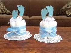 two baby feet on top of a cake with blue ribbon and white frosting sitting on a table in front of a couch