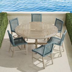 an outdoor table and chairs on a balcony overlooking the water with grass growing around it