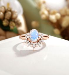 a close up of a ring on a white surface with flowers in the back ground