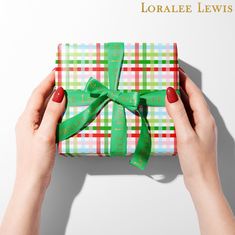 a woman holding a wrapped present box with green ribbon on it's wrapper