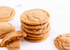 a pile of cookies sitting on top of a white counter next to each other with one broken cookie in the middle