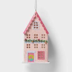 a pink house ornament hanging on a white wall