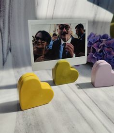 three heart shaped magnets sitting on top of a table next to a photo frame