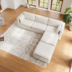 a large white sectional sofa sitting on top of a hard wood floored living room