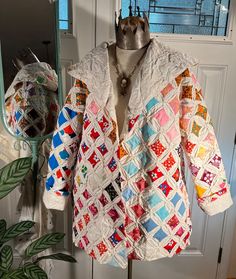 a colorful jacket hanging on a door with a mirror in the background and potted plant next to it