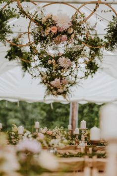 a table with flowers and candles under a white tented area for an outdoor wedding