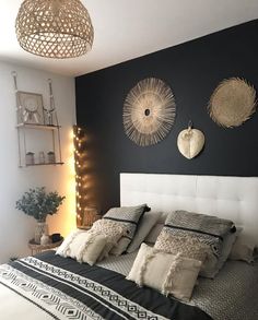 a bedroom with black walls and white bedding, lights on the headboard and pillows