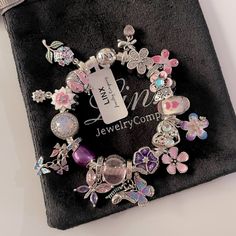 a close up of a bracelet on a black cloth with flowers and butterflies around it