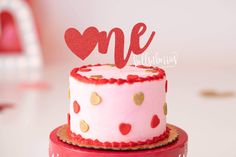 a pink cake with gold polka dots and a red one on top that says me