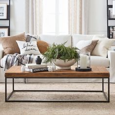 a living room with white couches, coffee table and pictures on the wall behind it