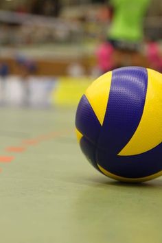 a blue and yellow volleyball sitting on top of a court