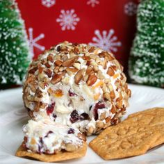 a white plate topped with an ice cream ball and crackers next to christmas trees