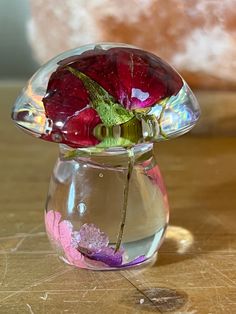 a glass vase filled with flowers on top of a wooden table