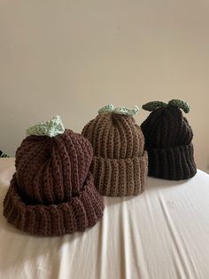 three knitted hats sitting on top of a bed