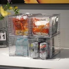 three plastic containers with drinks and snacks in them on a table next to a vase