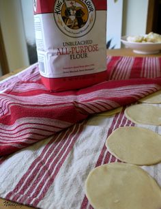 floured flatbreads sitting on a red and white towel next to a bag of flour