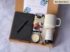 an open box containing coffee, candles, and other items for a woman's day