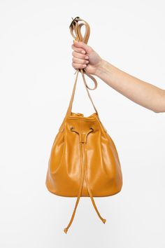 The Drawstring Bucket Bag is a classic that combines style and function. You’ll find that this spacious bag fits easily into your daily wardrobe. This artisanal product is made of genuine leather. All scars are characteristics of the skin and not imperfections. We hope you enjoy this unique handmade object. | Drawstring Bucket Bag for Women in Dijon Versatile Brown Bucket Bag With Leather Lining, Leather Lining Bucket Bag, Cognac Bucket Bag With Dust Bag Included, Everyday Leather Handle Pouch Bucket Bag, Versatile Leather Bucket Bag With Leather Lining, Versatile Leather Satchel With Dust Bag, Classic Everyday Pouch With Leather Lining, Classic Soft Leather Pouch For Daily Use, Soft Leather Bucket Bag In Cognac For On-the-go