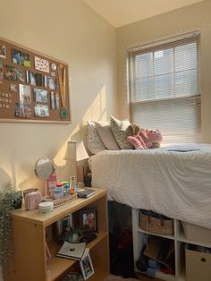 a bedroom with a bed, desk and shelves in front of the window that have pictures on it