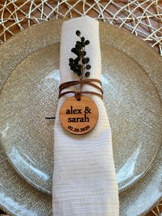 a silver plate with a white napkin on it and a wooden place card that says alex & saran