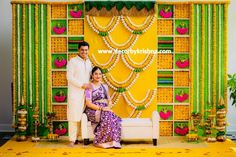 a man and woman standing next to each other in front of a wall with decorations