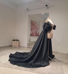 a mannequin with a black dress on display in an art gallery, next to a mirror