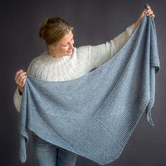 a woman is holding up a blue shawl