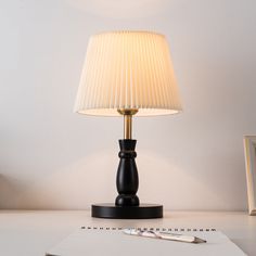 a lamp sitting on top of a desk next to a notepad and pencils