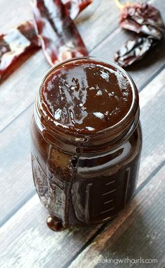 a jar filled with chocolate spread sitting on top of a wooden table next to bacon strips