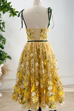 a yellow dress with flowers on it sitting on a mannequin