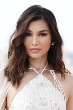 an image of a woman with long hair wearing a white dress and posing for the camera