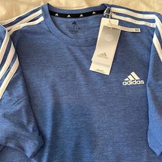 Brand New. Never Worn. Tags Attached. Adidas Multi Sport Tee Shirt. Short Sleeve. Size Medium. Regular Fit. Shoulder To Shoulder 17”. Armpit To Armpit 21”. Length 29”. Royal Blue Heather With 3 White Stripes. 65% Recycled Polyester. 35% Cotton. Adidas Blue Three Stripes Top, Adidas Blue Tops With Three Stripes, Blue Adidas Tops With Three Stripes, Adidas Blue Long Sleeve Tops, Blue Adidas Long Sleeve Tops, Adidas Blue Tops With Three Stripes Branding, Blue Cotton Tops With Three Stripes, Blue Adidas Tops With Three Stripes Branding, Adidas Blue Sporty Shirt