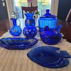 blue glass dishes and vases sitting on a table