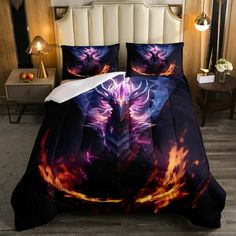 a bed covered in a black and orange comforter with an image of a demon on it