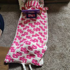 a crocheted pink and white blanket laying on the floor next to a child's bed