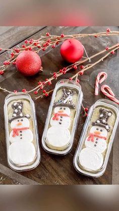 three tins with snowmen on them sitting next to candy canes and ornaments