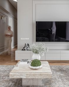 a living room with white furniture and a flat screen tv mounted on the wall above it